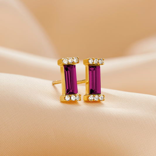Gold stud earring set with an amethyst baguette cut Swarovski crystal topped with pavé set clear crystals in the ends of each stone setting by Claudette Worters.