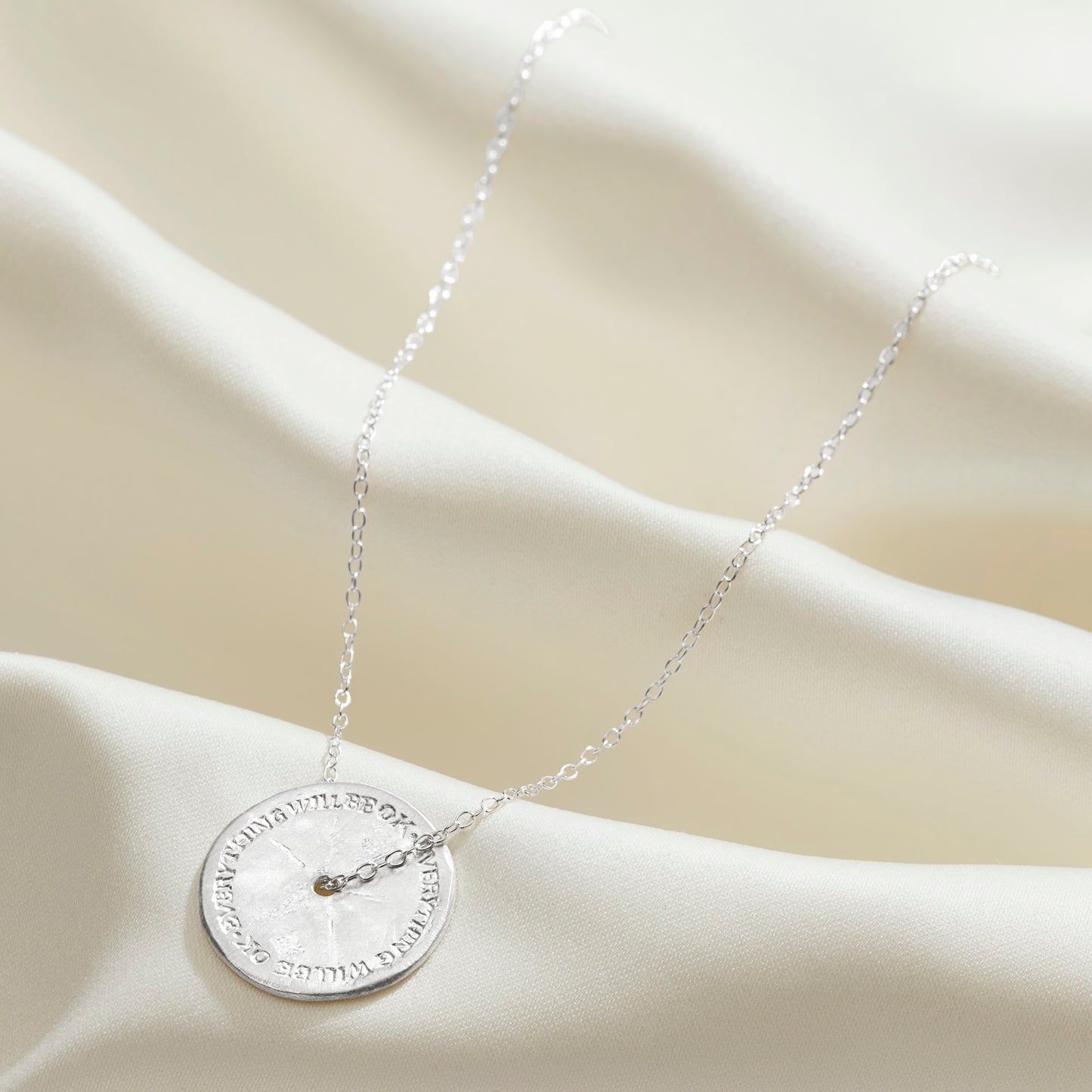 Stress necklace for anxiety relief in silver with the words Everything Will Be OK hand engraved around the disc pendant
