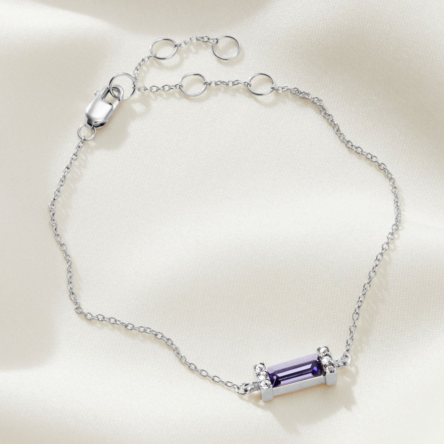 Deep purple tanzanite baguette shaped crystal in a sterling silver pavé setting on a delicate sterling silver trace chain to form a bracelet with a lobster claw fastening.