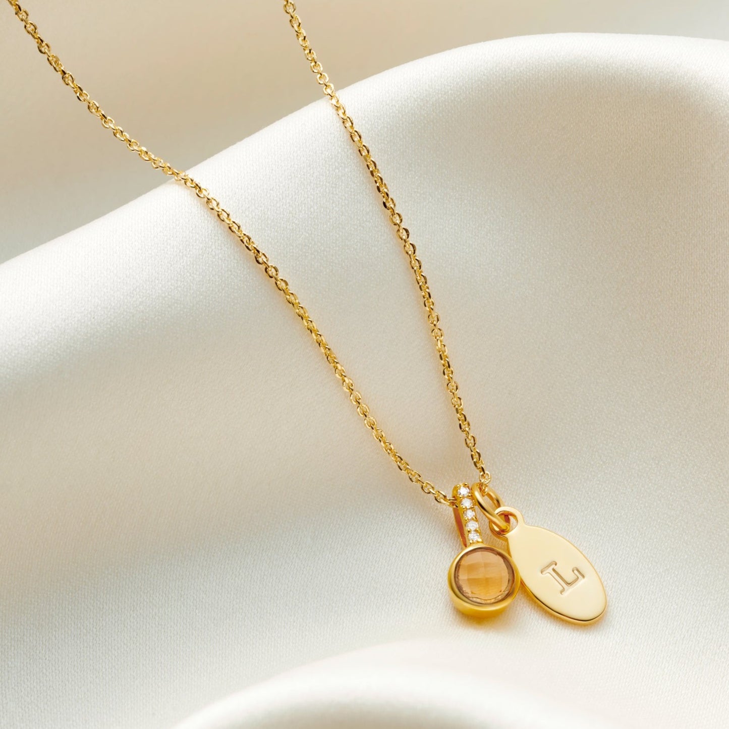 Yellow faceted citrine pendant in 18 carat gold vermeil with little white diamonds in the bale. Pendant is hung on a fine trace chain with the little oval charm that has been personalised with a capital letter L.
