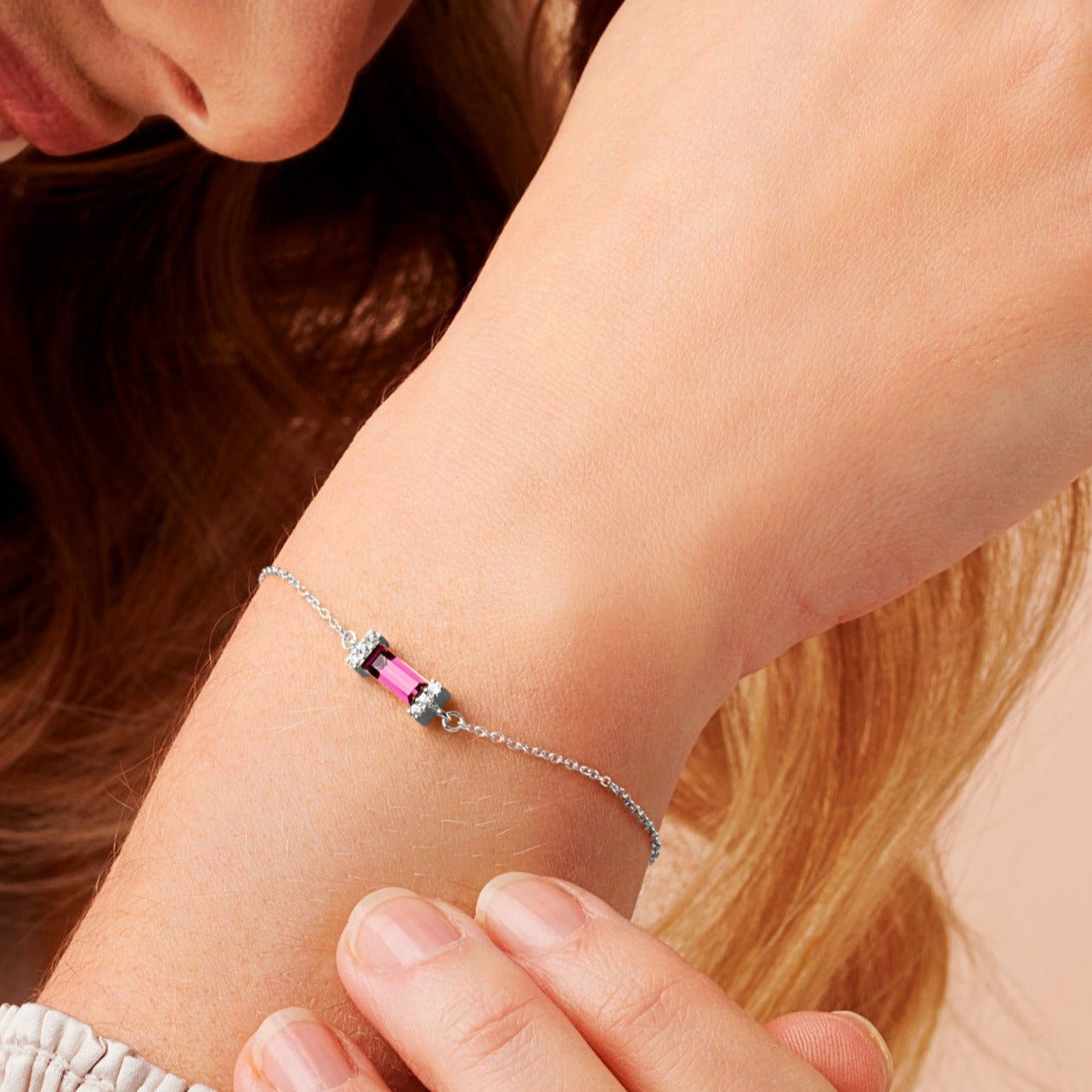 Woman wearing a silver bracelet on her wrist with a baguette shaped amethyst crystal on a fine silver trace chain.