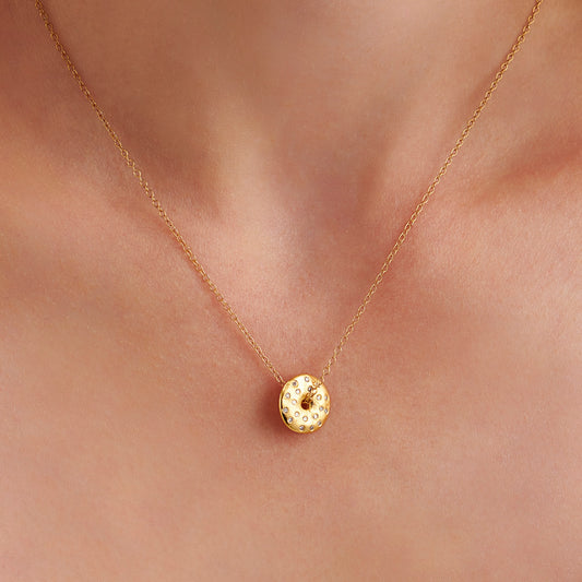 Organic gold vermeil moon phase necklace on model, set with natural diamonds on textured gold lunar disc pendant with a hole in the centre with a chain threaded through the centre by Claudette Worters.
