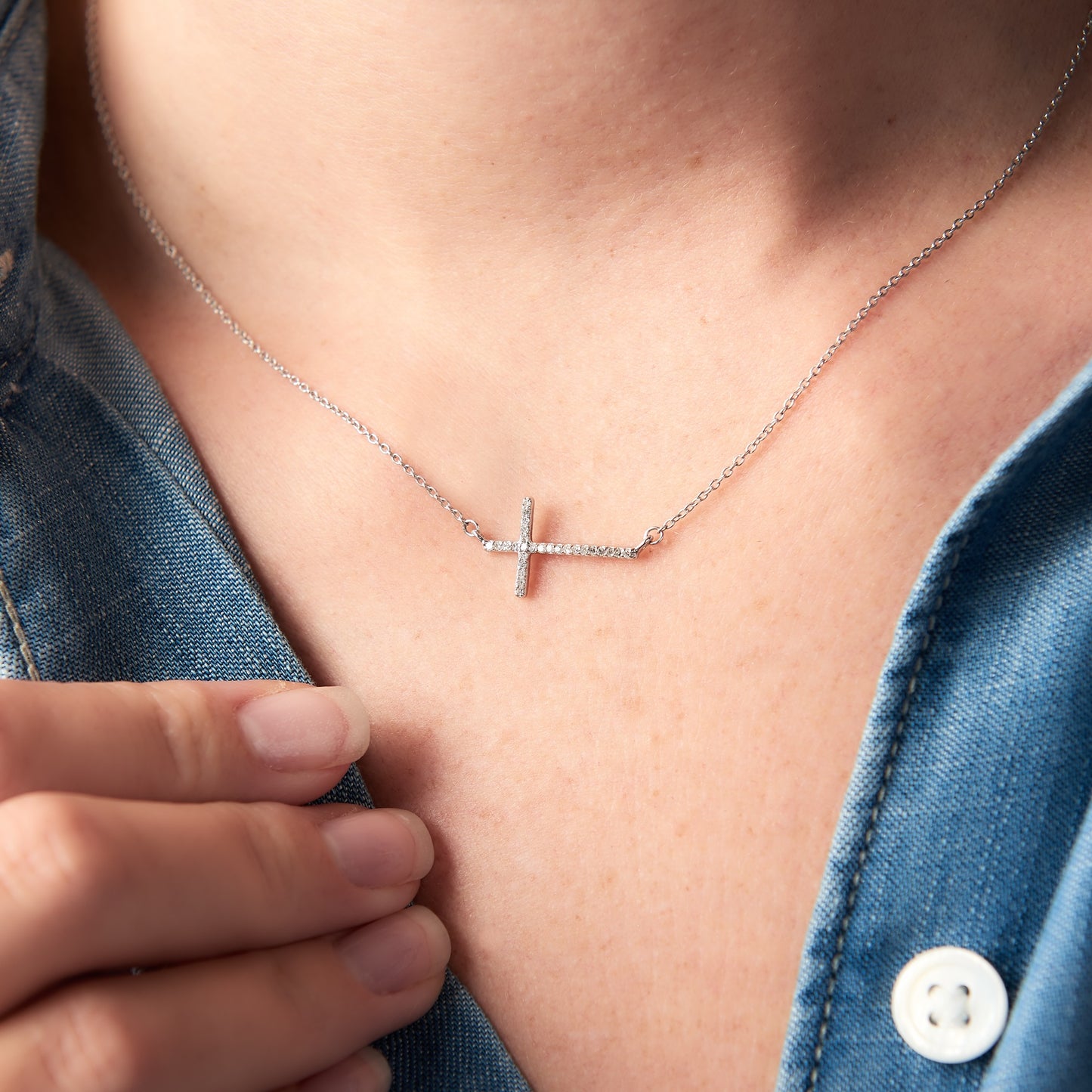 A cross necklace set with tiny diamonds. The cross runs sideways across the necklace and it's suspended on fine sterling silver trace chain.