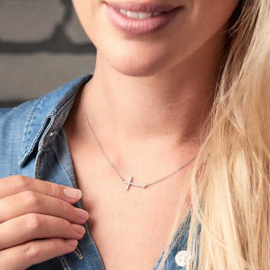 Silver cross necklace with the cross running sideways across the necklace. The cross is pavé set with diamonds.