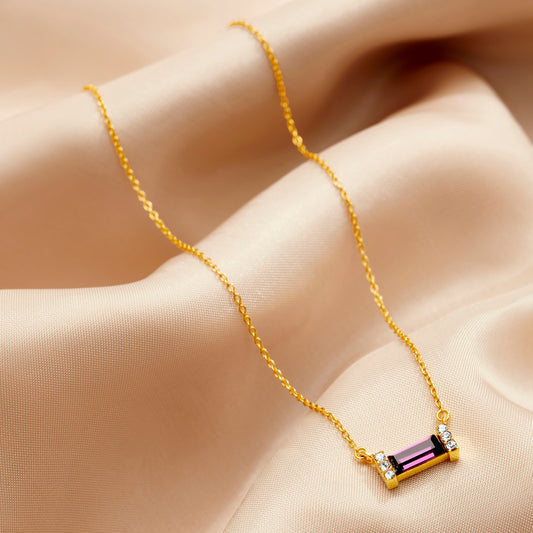 Purple amethyst crystal baguette pendant with tiny white crystals in each end. Metalwork is gold plated sterling silver and the pendant is on a fine gold vermeil trace chain.