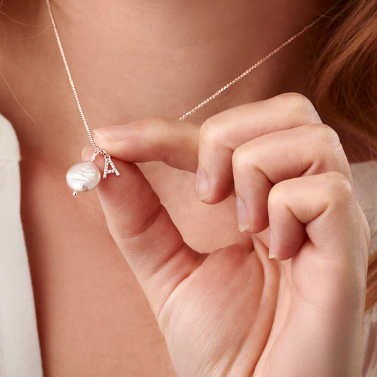 Letter A pendant in silver, pavé set with real tiny white diamonds hung along side an off white freshwater pearl disc pendant on a fine sterling silver trace chain by Claudette Worters.