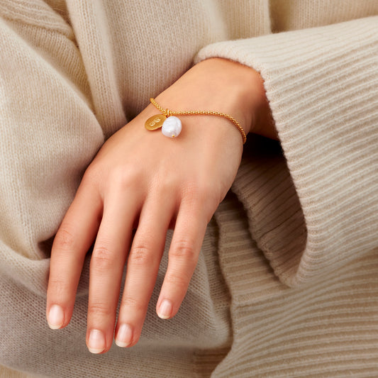 Personalised gold bracelet with large white pearl and initial charm.
