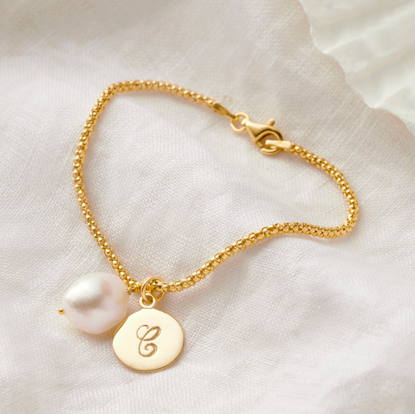 Personalised pearl bracelet in gold with initial charm by Claudette Worters