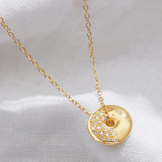 Gold moon phase necklace with a round half moon spinning pendant set with white diamonds