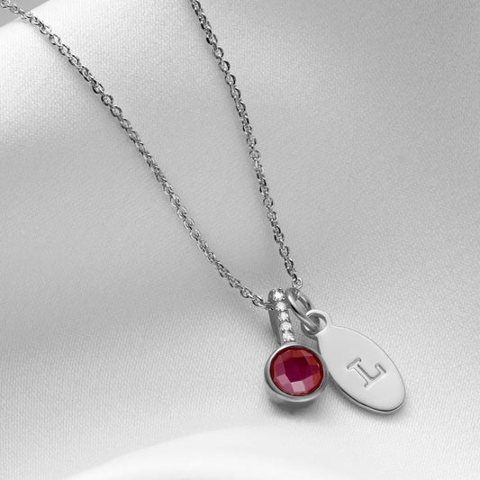 Faceted ruby pendant with tiny white diamonds in the bale in sterling silver, with a personalised initial charm on a fine trace chain.