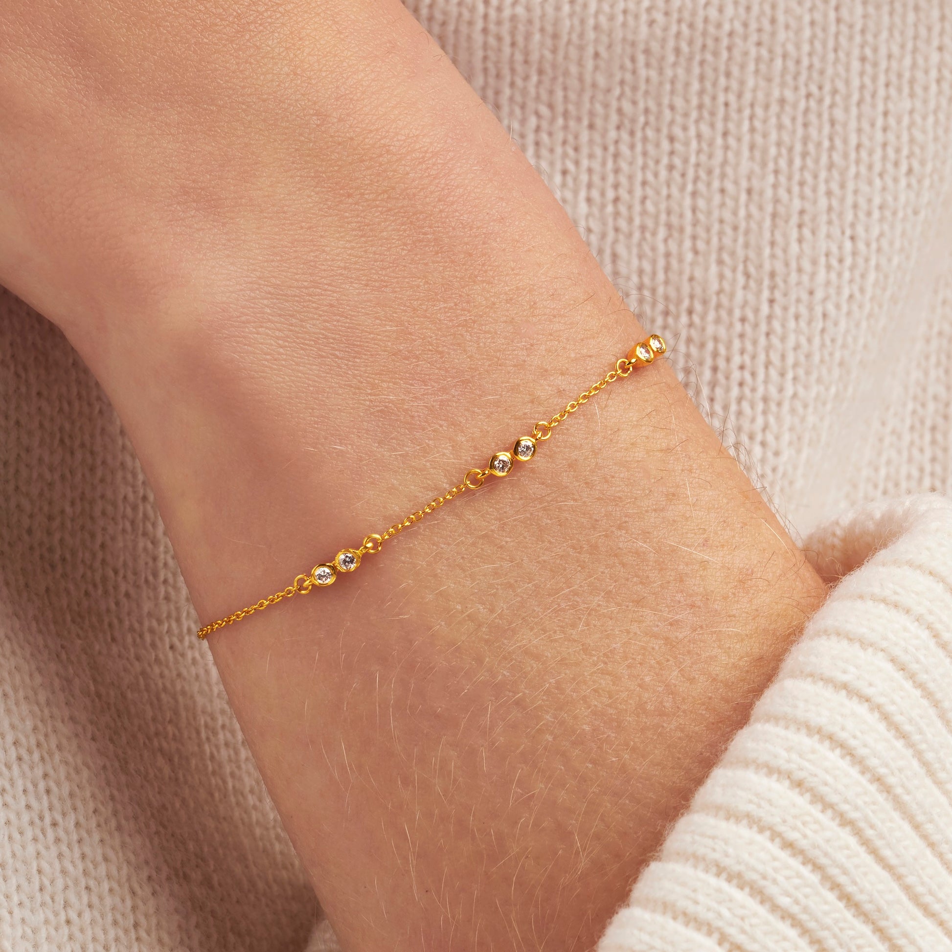 Gold bracelet on a wrist with 6 diamonds in gold bezels to represent 6 decades for 60th birthday