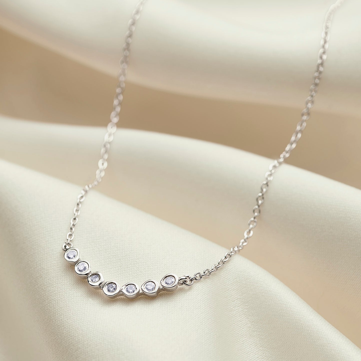 70th birthday necklace with a row of  7 diamonds to symbolise 7 decades in sterling silver on a dainty trace chain.