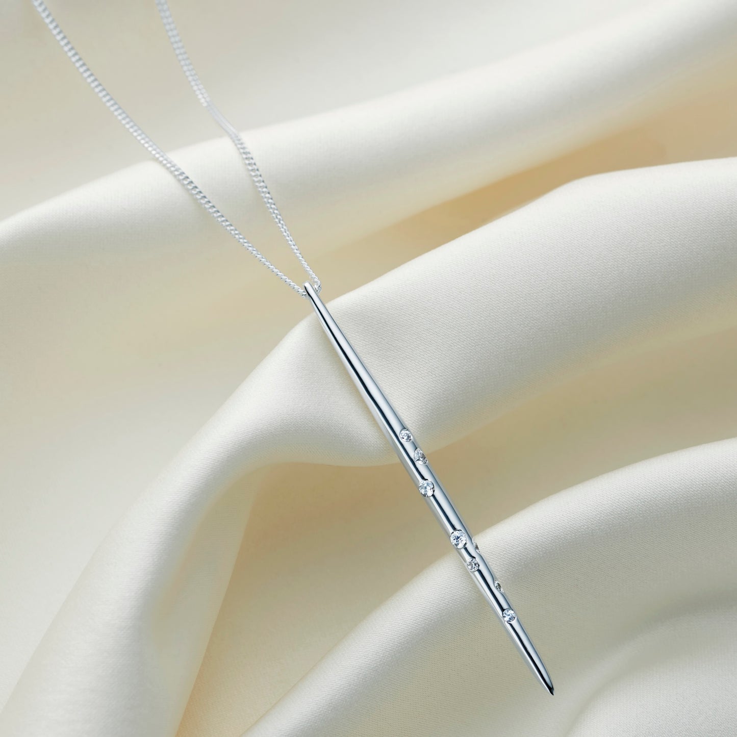 Polishing silver spike pendant set with white crystals in the pattern of the star constellation of Aquarius, hung on a fine sterling silver chain