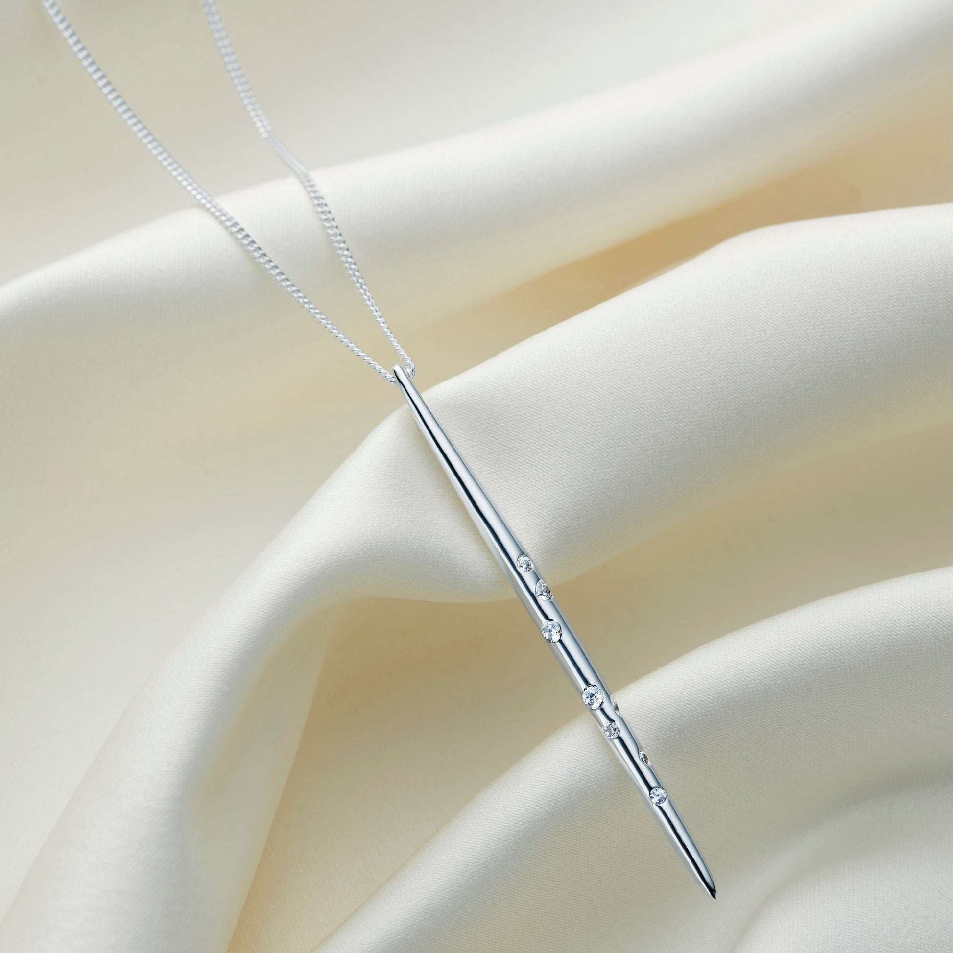 Polishing silver spike pendant set with white crystals in the pattern of the star constellation of Aquarius, hung on a fine sterling silver chain
