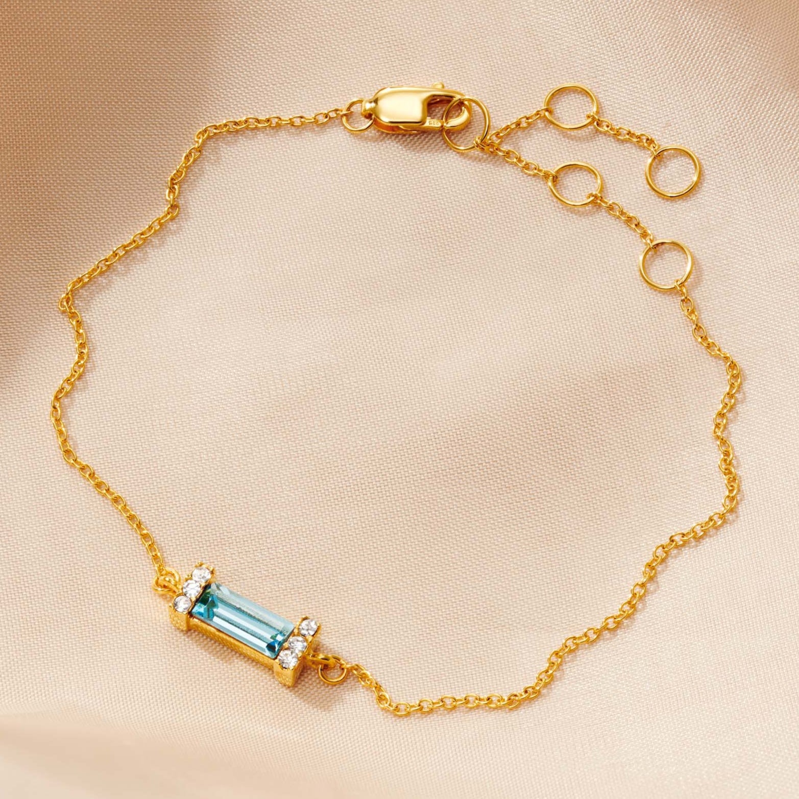 Aquamarine baguette cut crystal birthstone bracelet in gold vermeil with little white pavé crystals in either end of the settings.  Lobster claw fastening and adjustable fine trace chain.