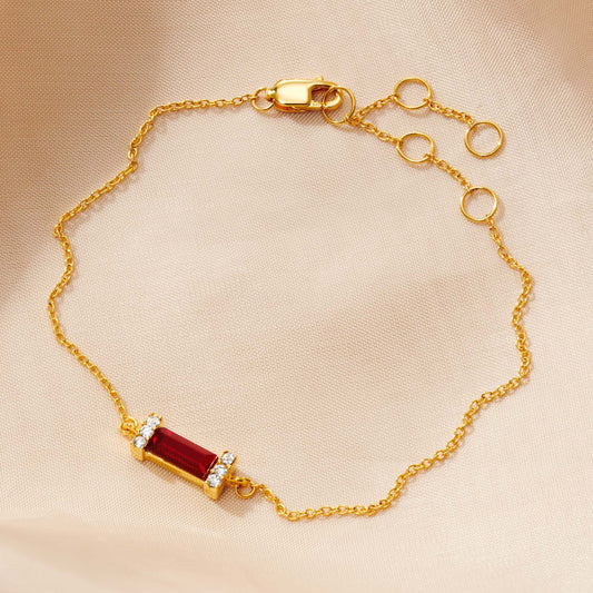 Dainty gold bracelet  with deep red garnet baguette crystal birthstone stone surrounded by tiny white crystals on a fine gold vermeil trace chain with a lobster claw fastening by Claudette Worters.