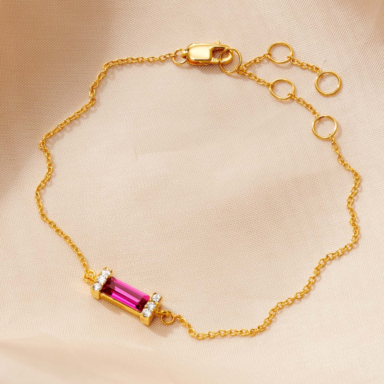 Gold adjustable bracelet with a focal baguette cut Ruby birthstone for the month of July.