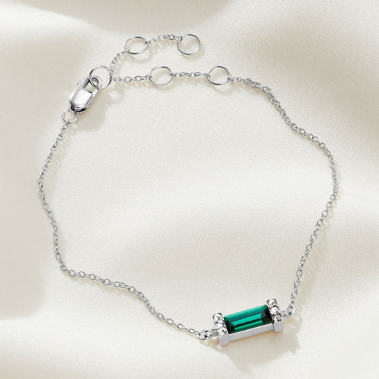 Sterling silver bracelet with an emerald crystal baguette shaped stone with pavé setting on a fine silver trace chain with an extender chain and a lobster claw fastening.