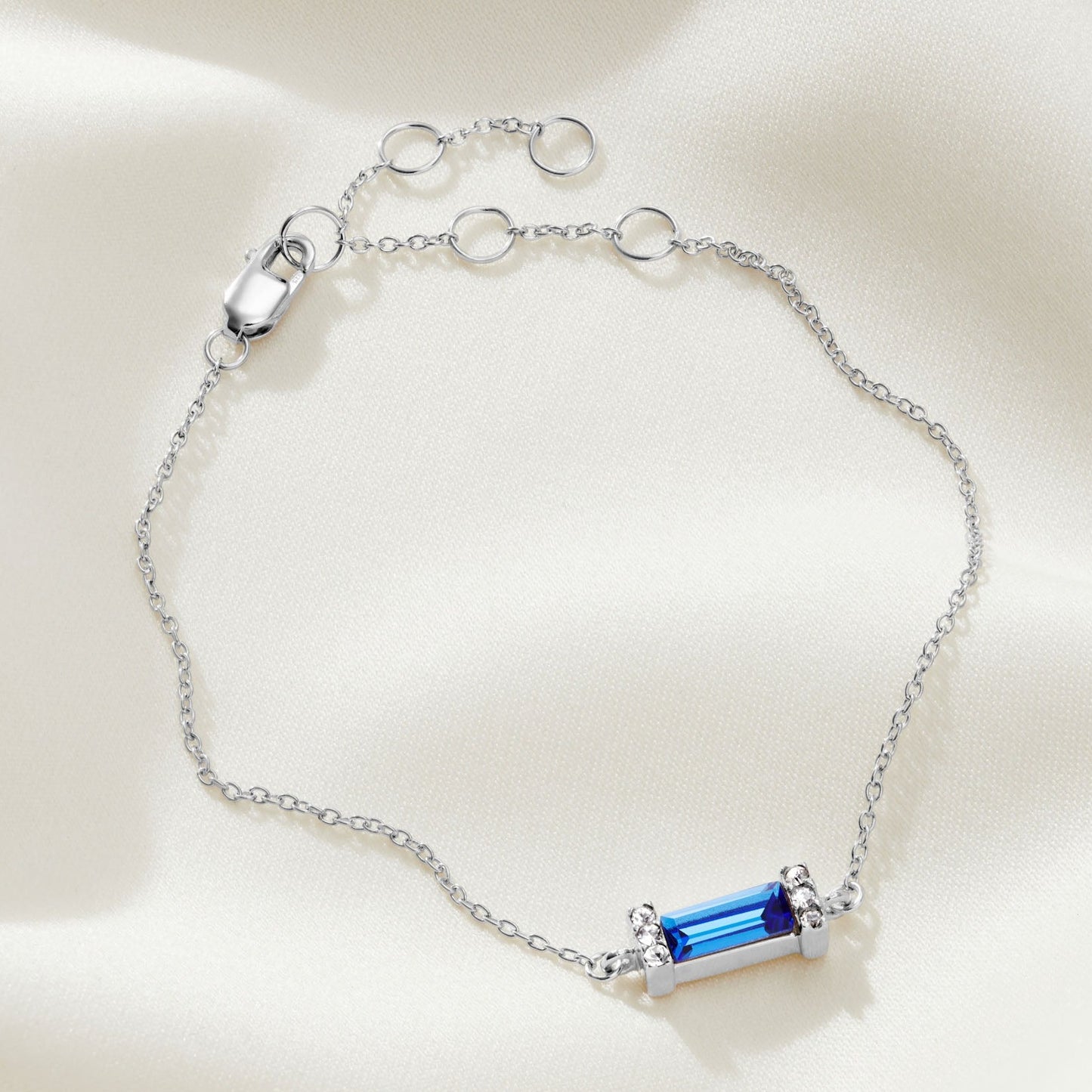 Bright blue sapphire baguette stone in a sterling silver setting on an adjustable sterling silver bracelet.