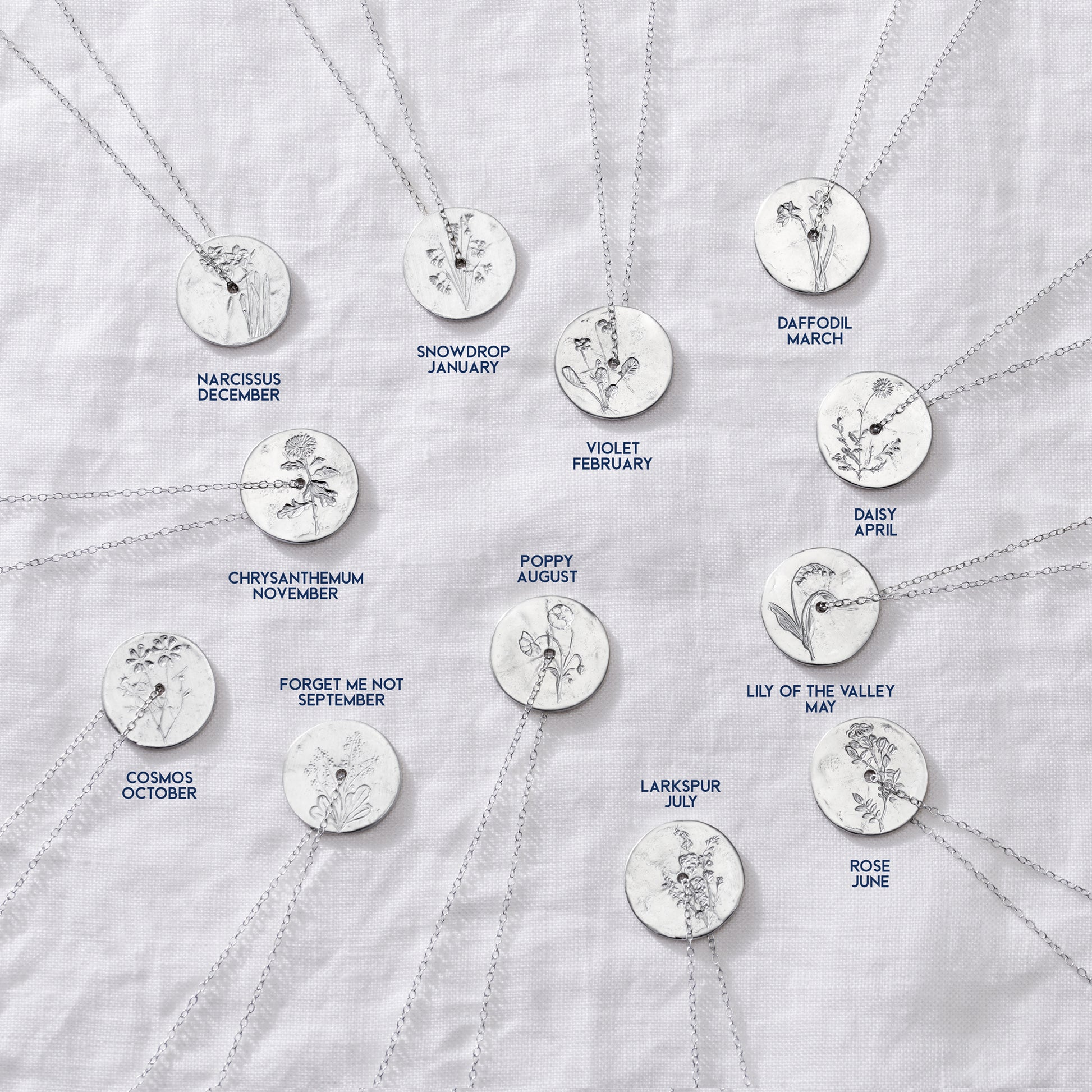 Group of 12 sterling silver disc pendants, each hand engraved with a birth flower for each month of the year on silver trace chains.