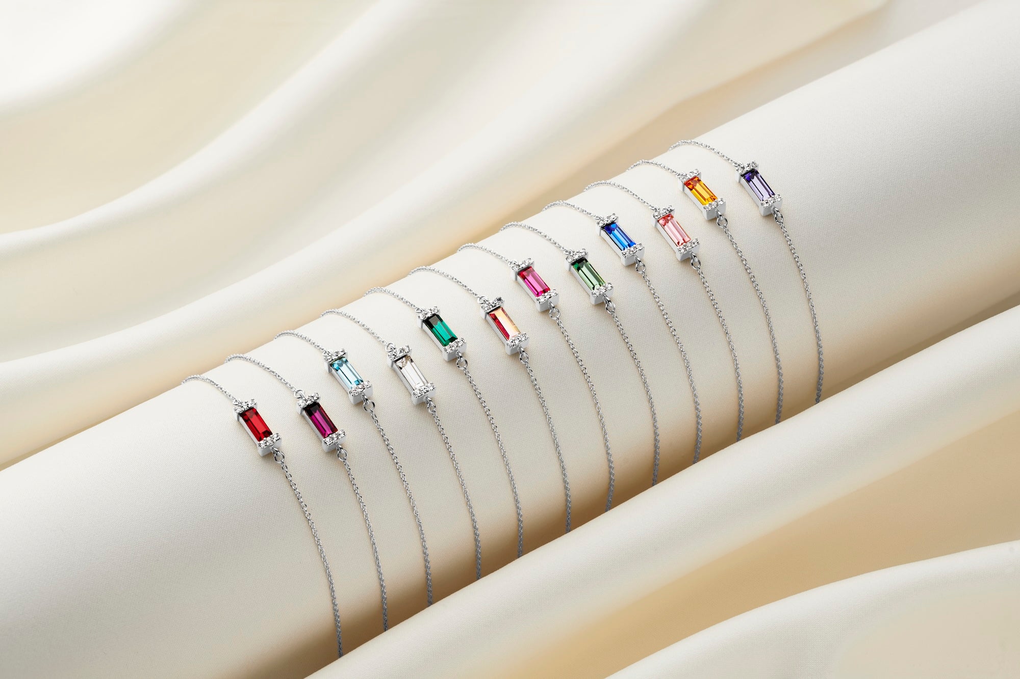 Row of 12 coloured baguette cut Swarovski crystal bracelets in an Art Deco style setting on a fine sterling silver trace bracelet chain.