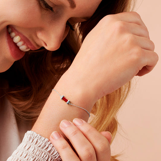 Woman wearing a silver bracelet on her wrist with a garnet red baguette cut stone with pavé crystal setting on a delicate silver trace chain 