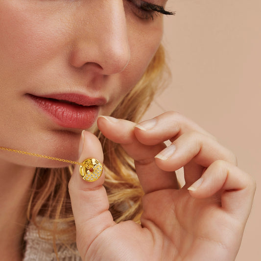 Close-up of a woman wearing a gold disc pendant with a hole in the centre set with real diamonds depicting the first quarter moon phase