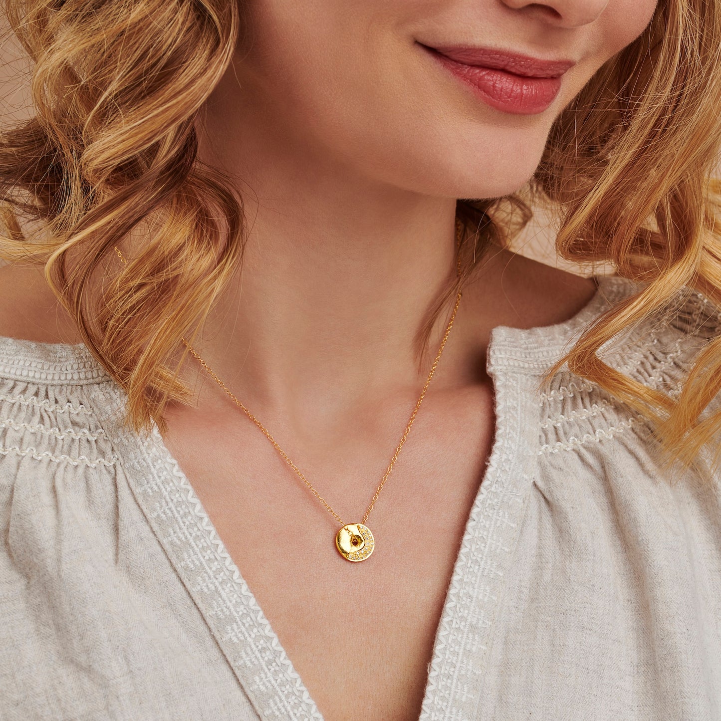 Claudette Worters gold vermeil abstract moon phase pendant necklace worn on model, with spinning textured disc and diamond detail in the pattern of a waxing crescent moon.