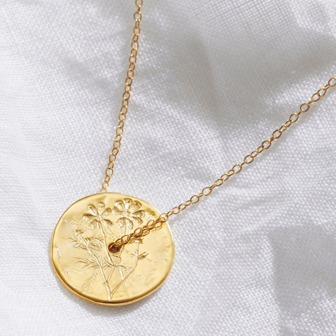 October birth flower pendant with a gold disc pendant, hand engraved with Cosmos flowers.  A fine gold trace chain runs through the centre of the gold circle pendant.