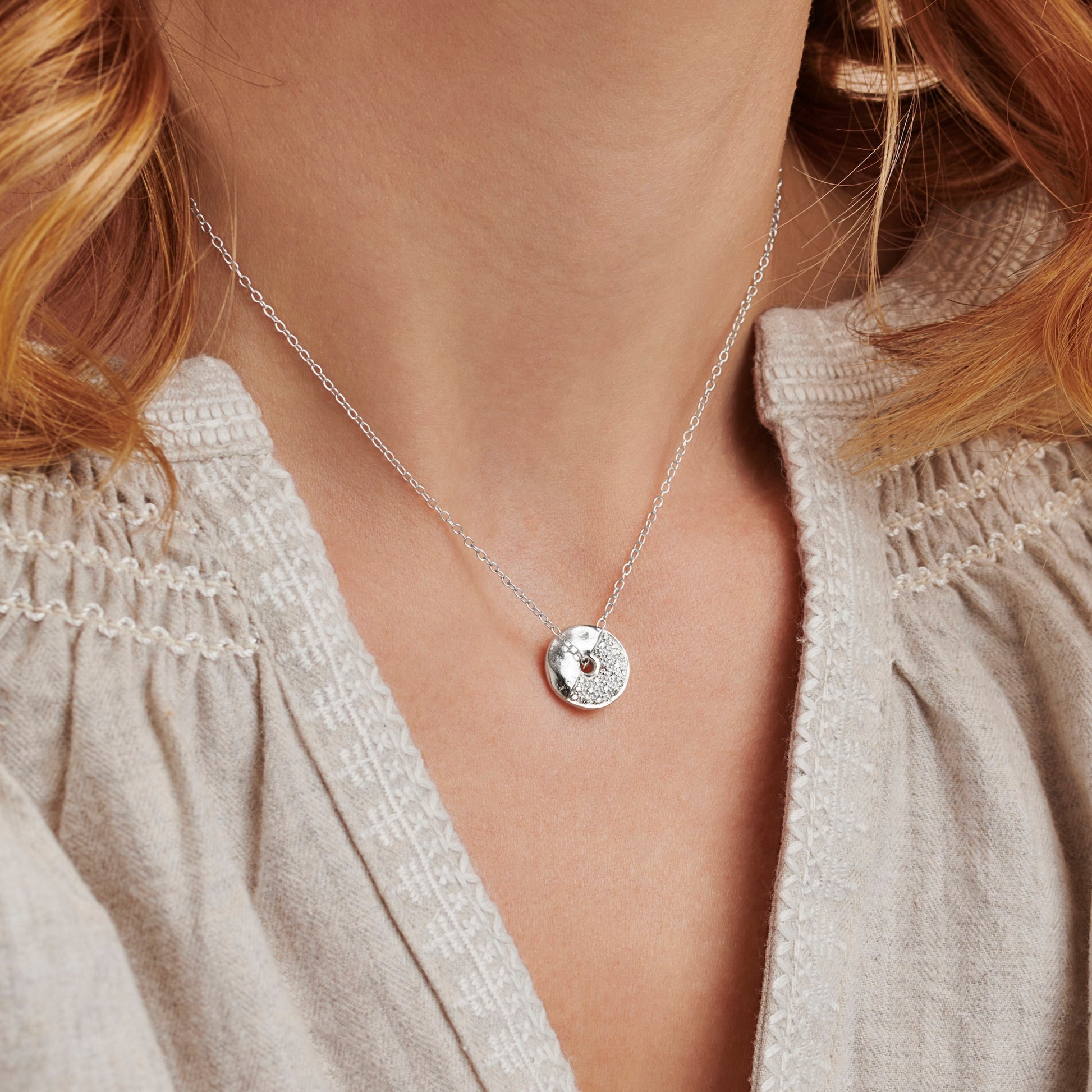 Round silver spinning pendant necklace set with diamonds to represent the First Quarter moon phase by Claudette Worters