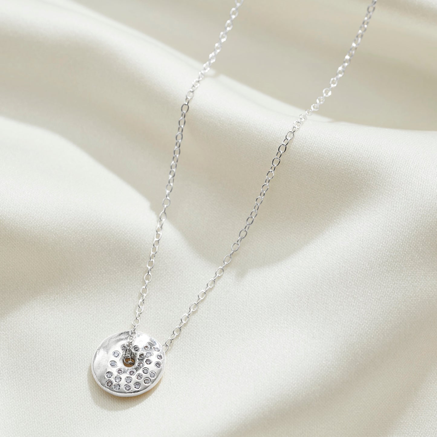 Moon cycle spinning disc necklace in silver, set with white diamonds in a waxing gibbous moon phase formation on a fine sterling silver trace chain