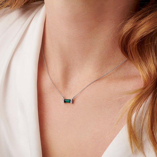 Woman wearing a green emerald baguette shaped crystal set in sterling silver on a fine silver trace chain.