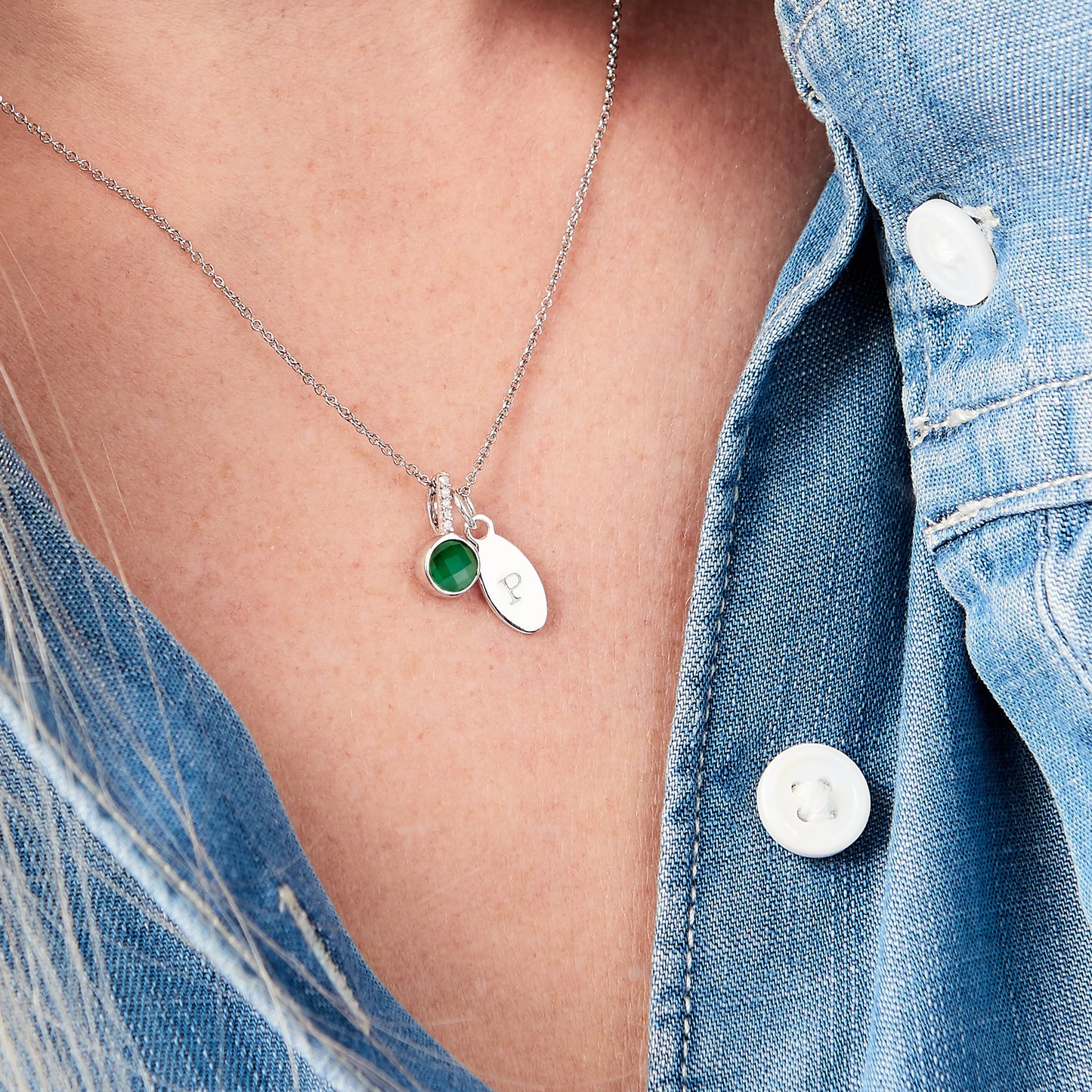 Real faceted emerald necklace on a fine sterling silver trace chain.  The emerald pendant is round and has a row of little white diamonds in the bale.  This is hung on the chain next to an oval charm that has been personalised with the letter P.  Necklace is by Claudette Worters.