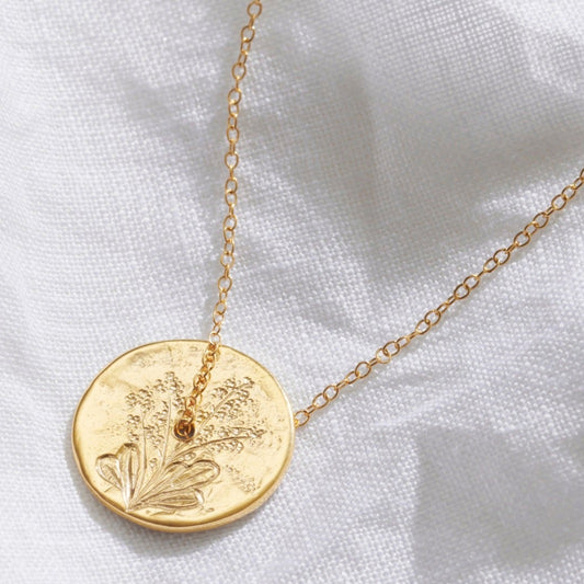 September birth flower spinner disc pendant necklace in gold vermeil with hand engraved forget me not flowers.  A delicate gold trace chain threads through the centre of the circle pendant.