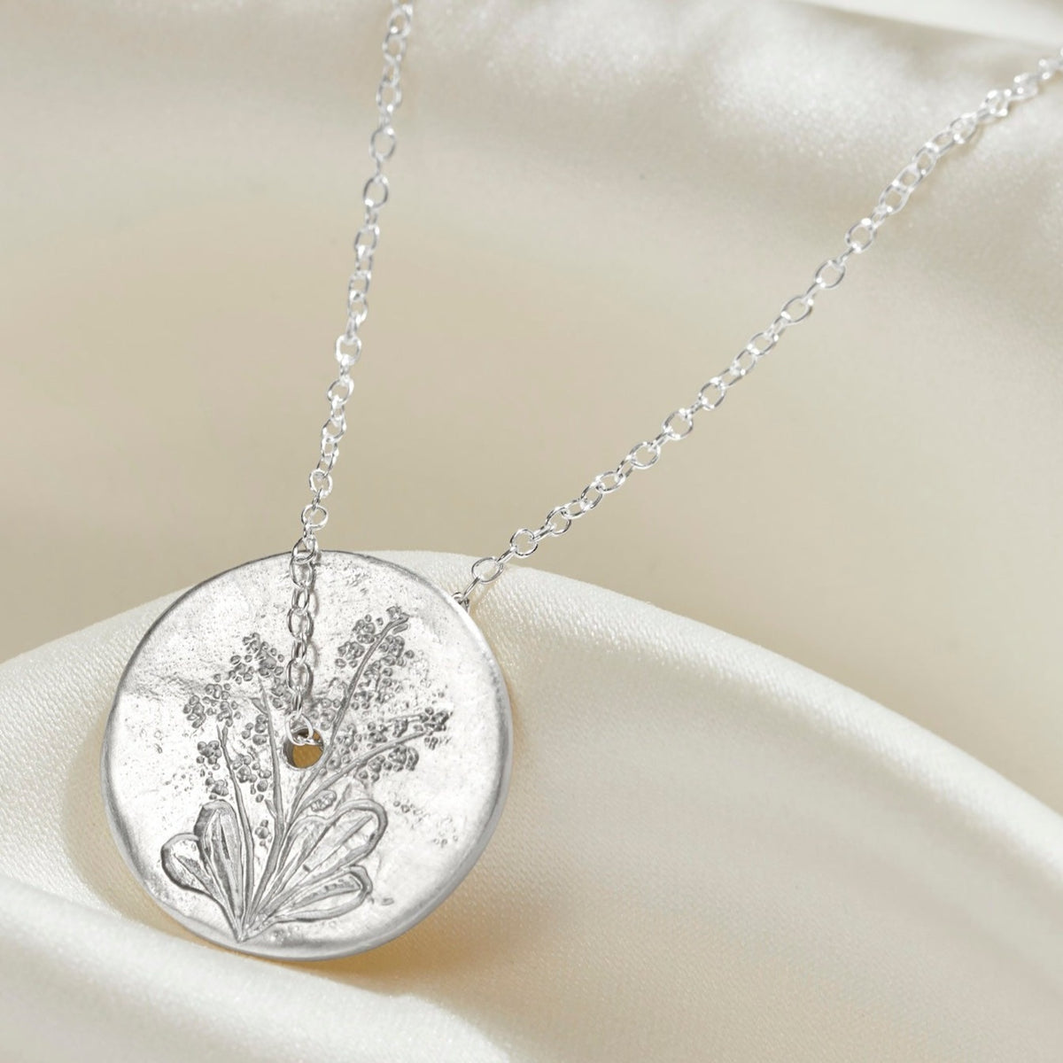 Birth flower spinner disc pendant in sterling silver with a hand engraved forget-me-not flower.  A fine sterling silver trace chain runs through the centre of the silver circle necklace.
