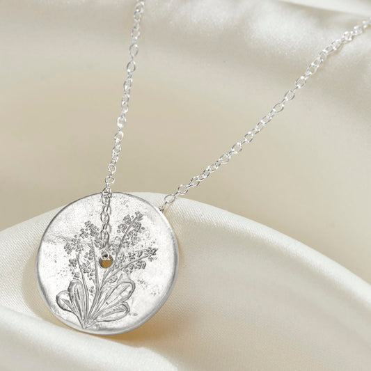 Birth flower spinner disc pendant in sterling silver with a hand engraved forget-me-not flower.  A fine sterling silver trace chain runs through the centre of the silver circle necklace.