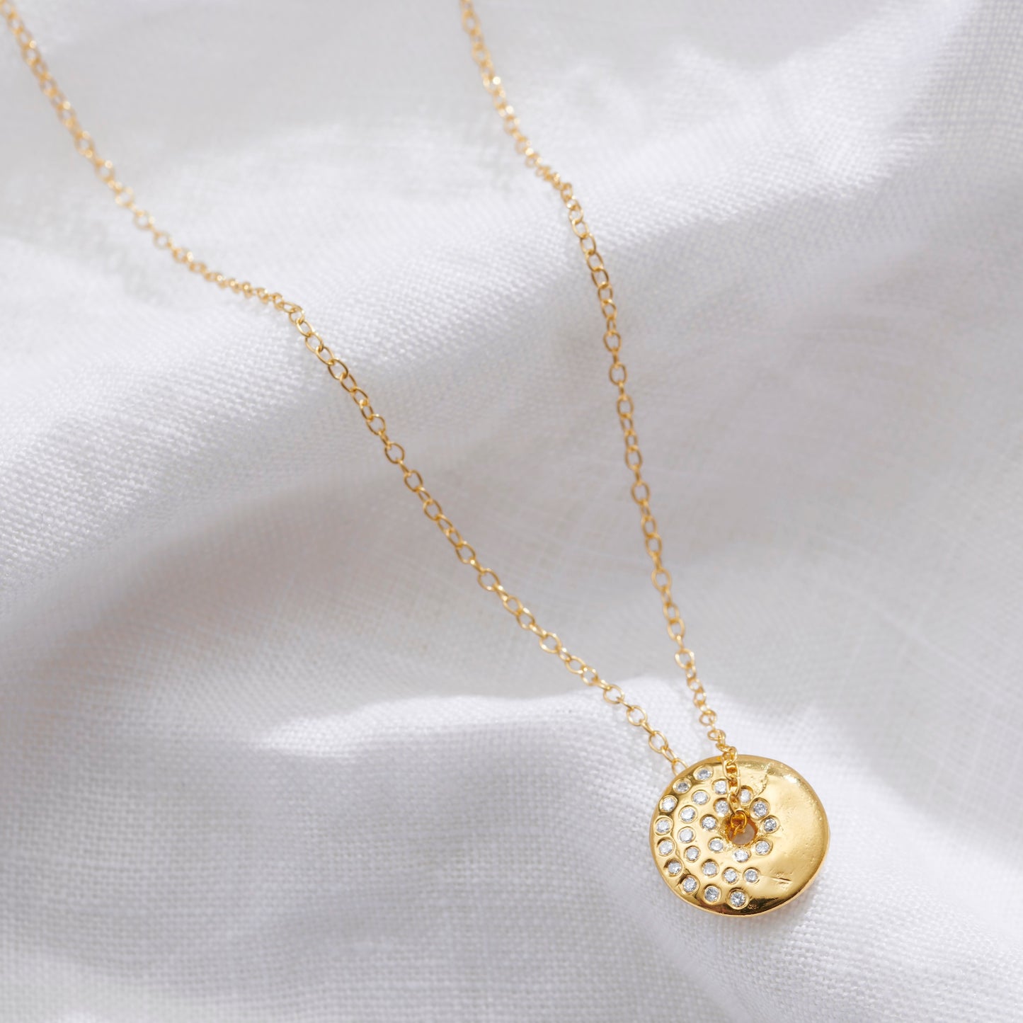 Gold moon phase necklace with a circular pendant set with sparkling white diamonds in the waning gibbous moon phase by Claudette Worters