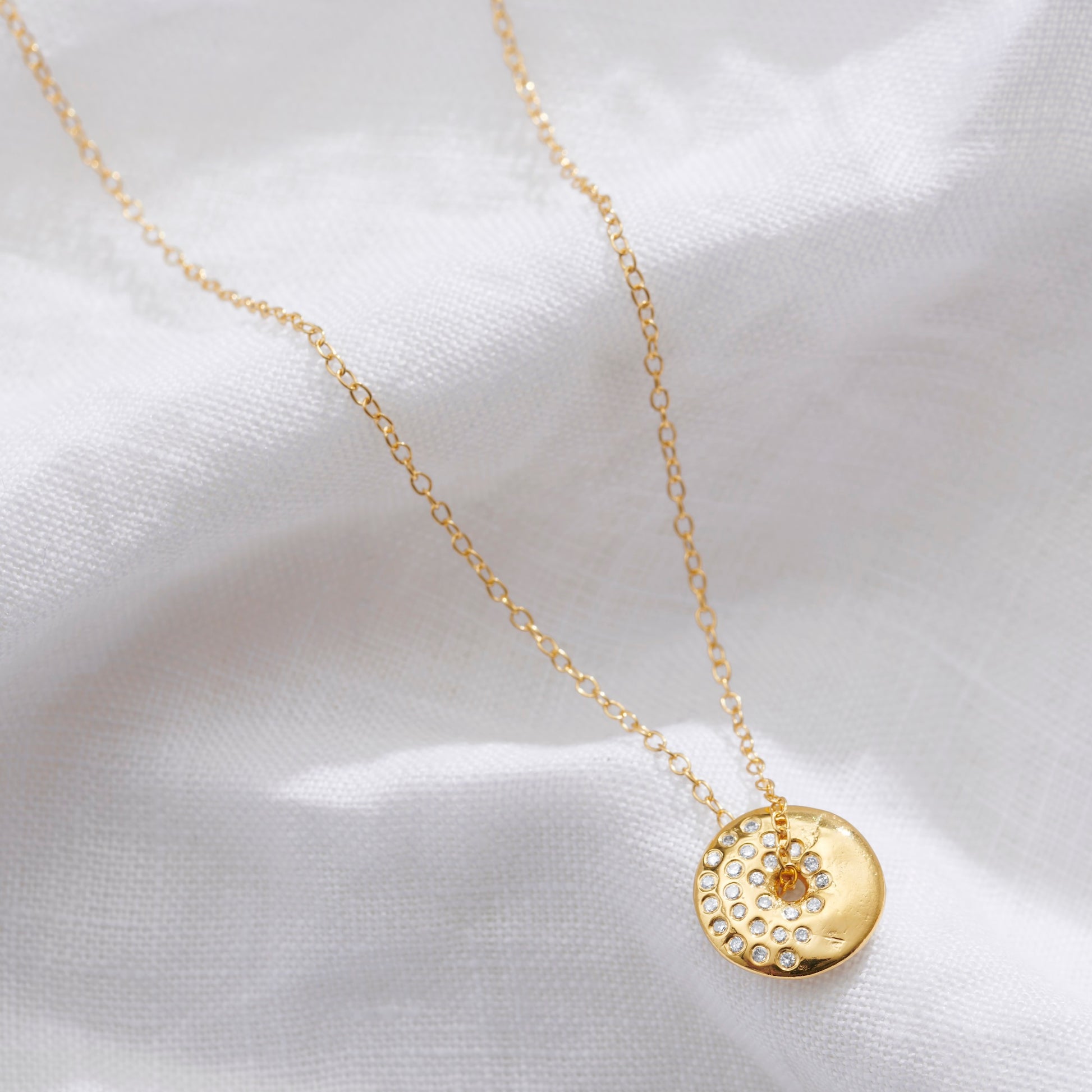 Gold moon phase necklace with a circular pendant set with sparkling white diamonds in the waning gibbous moon phase by Claudette Worters