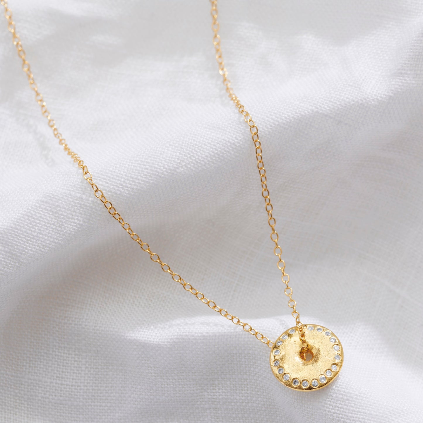 Gold spinning New Moon pendant in 18 carat gold vermeil with lunar surface texture and tiny diamonds by Claudette Worters