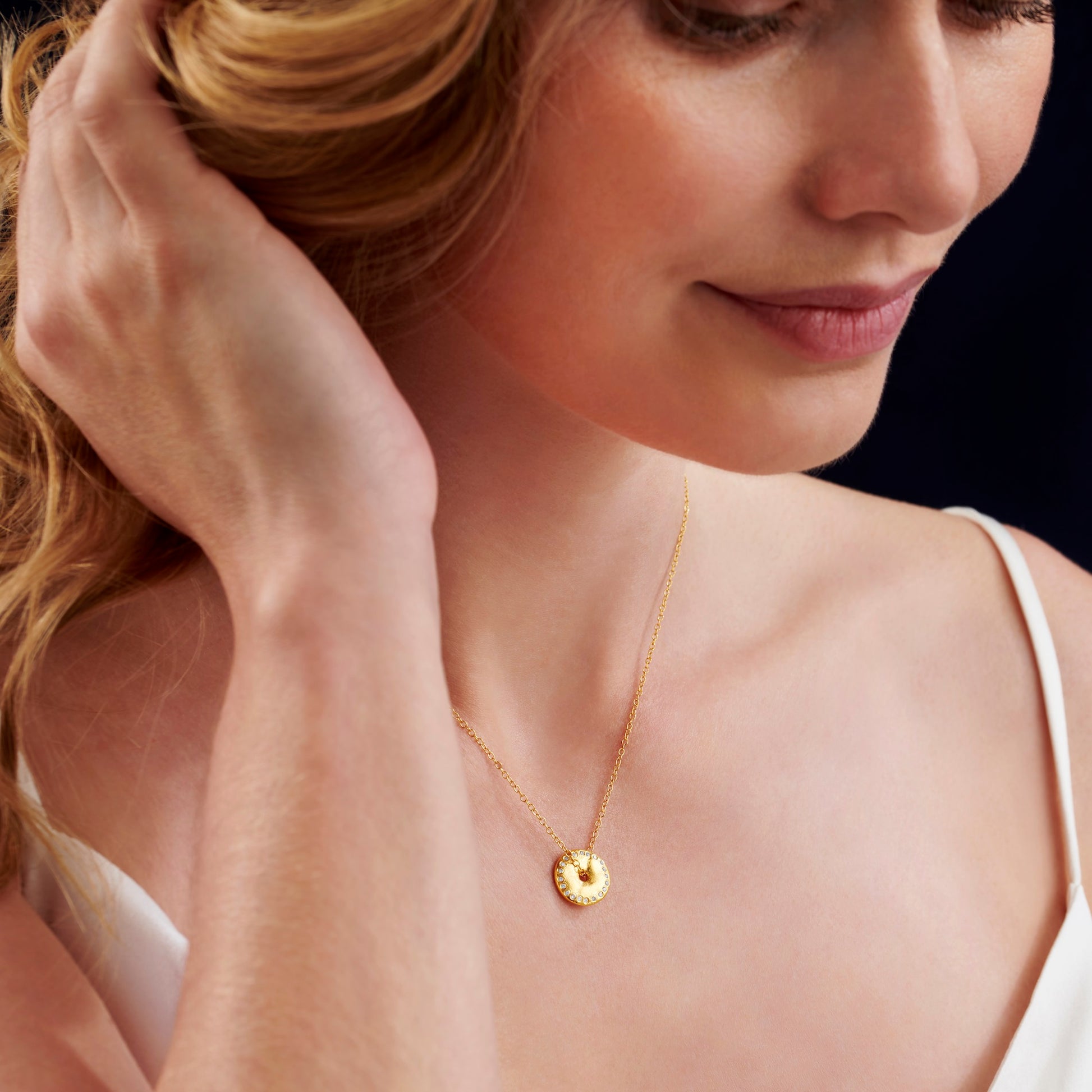 18 carat gold vermeil New Moon pendant necklace by Claudette Worters. Small spinning disc with textured lunar surface and tiny natural diamonds along the edge, on a fine gold chain.