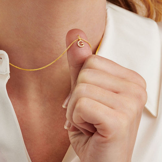 Gold initial pendant set with tiny white diamonds on a fine gold trace chain.
