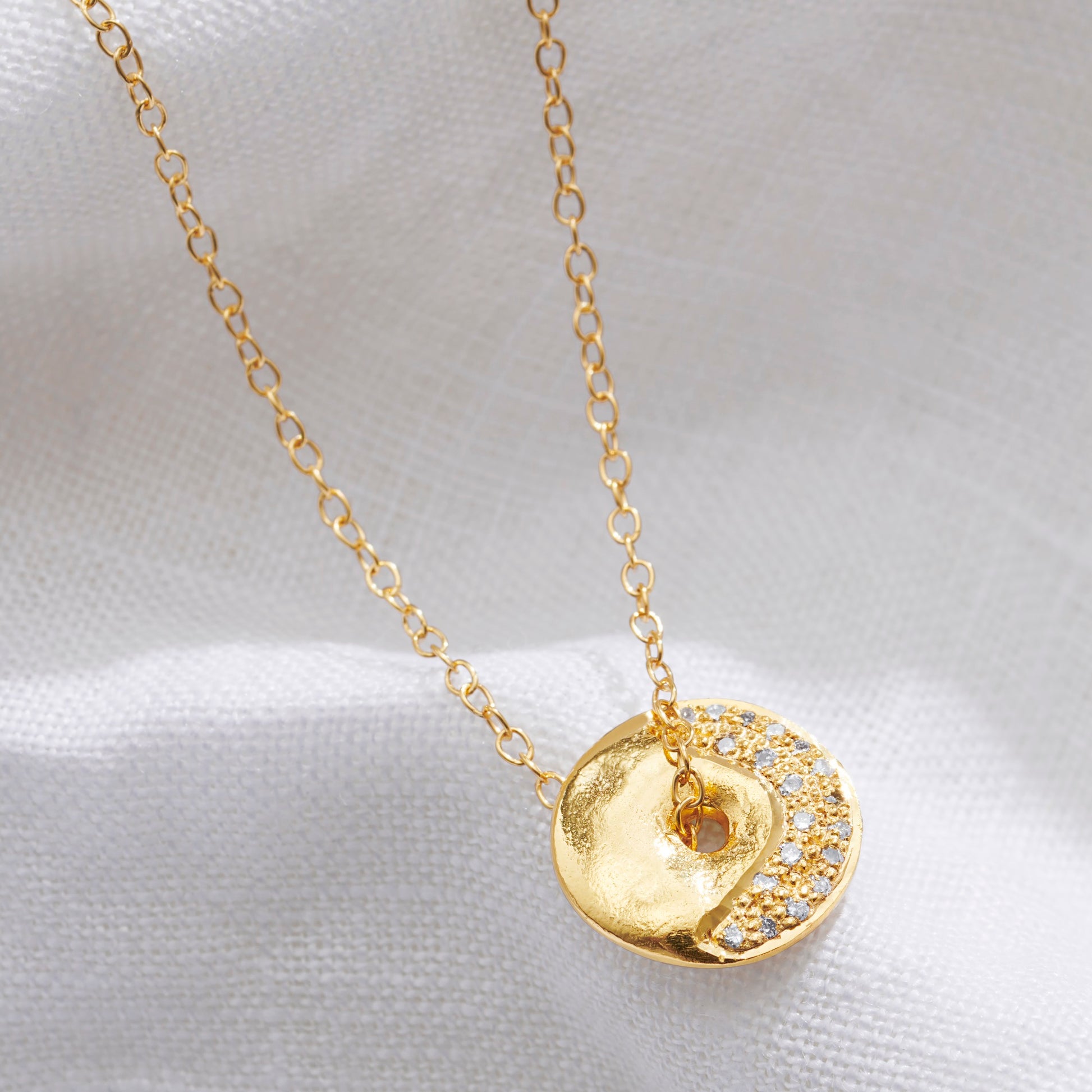 Gold vermeil Waxing Crescent moon phase necklace by Claudette Worters. Spinning textured lunar disc with small natural diamonds highlighting the crescent shape, on a delicate gold chain.