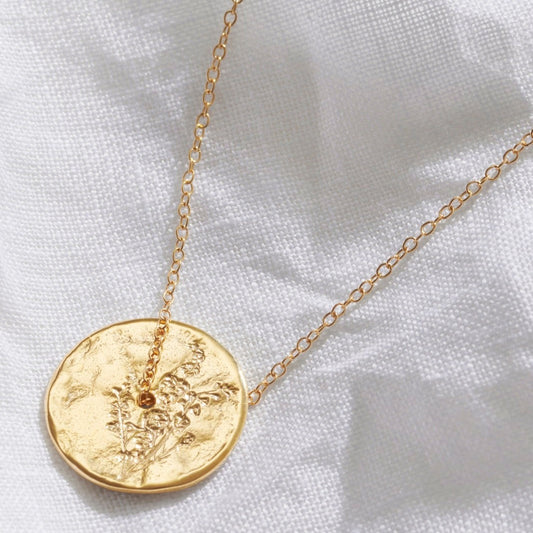 Gold spinner disc pendant with a delicate hand engraved Larkspur July birth flower on the surface.  A dainty gold vermeil trace chain threads through the centre of the pendant.