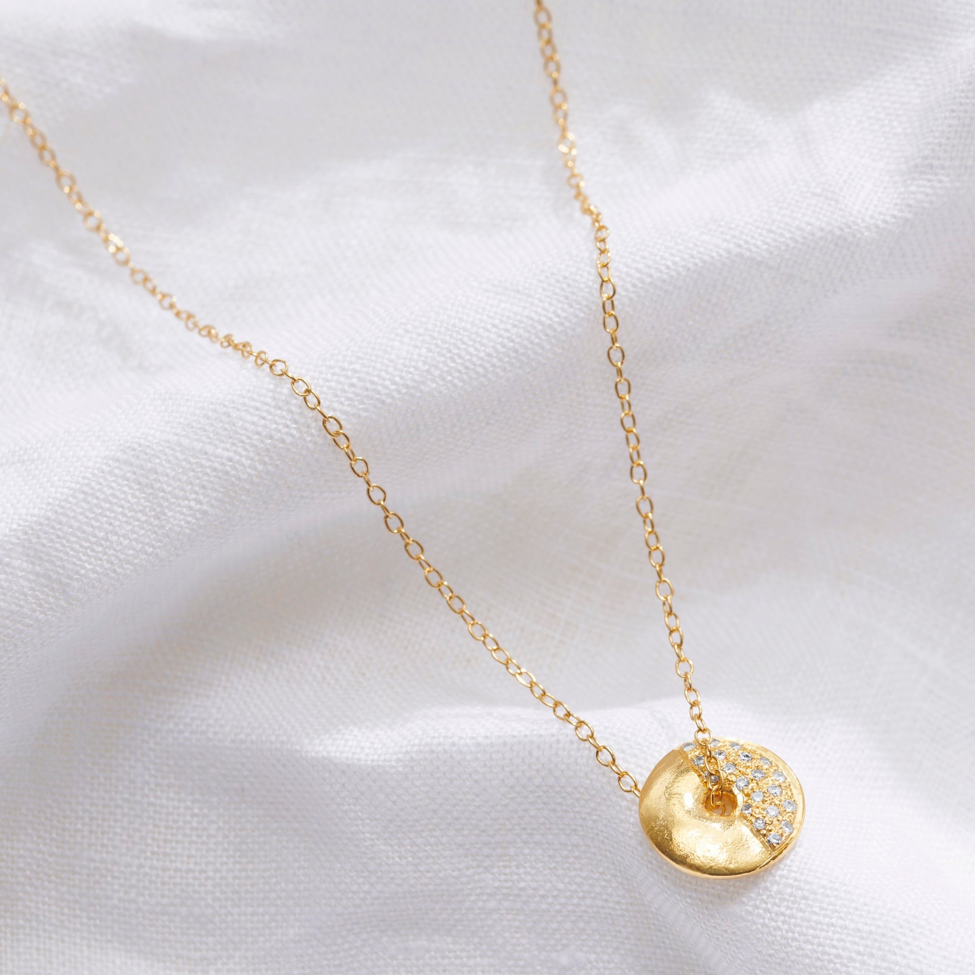 Gold vermeil First Quarter moon phase necklace by Claudette Worters with spinning textured lunar disc pendant set with real white diamonds.