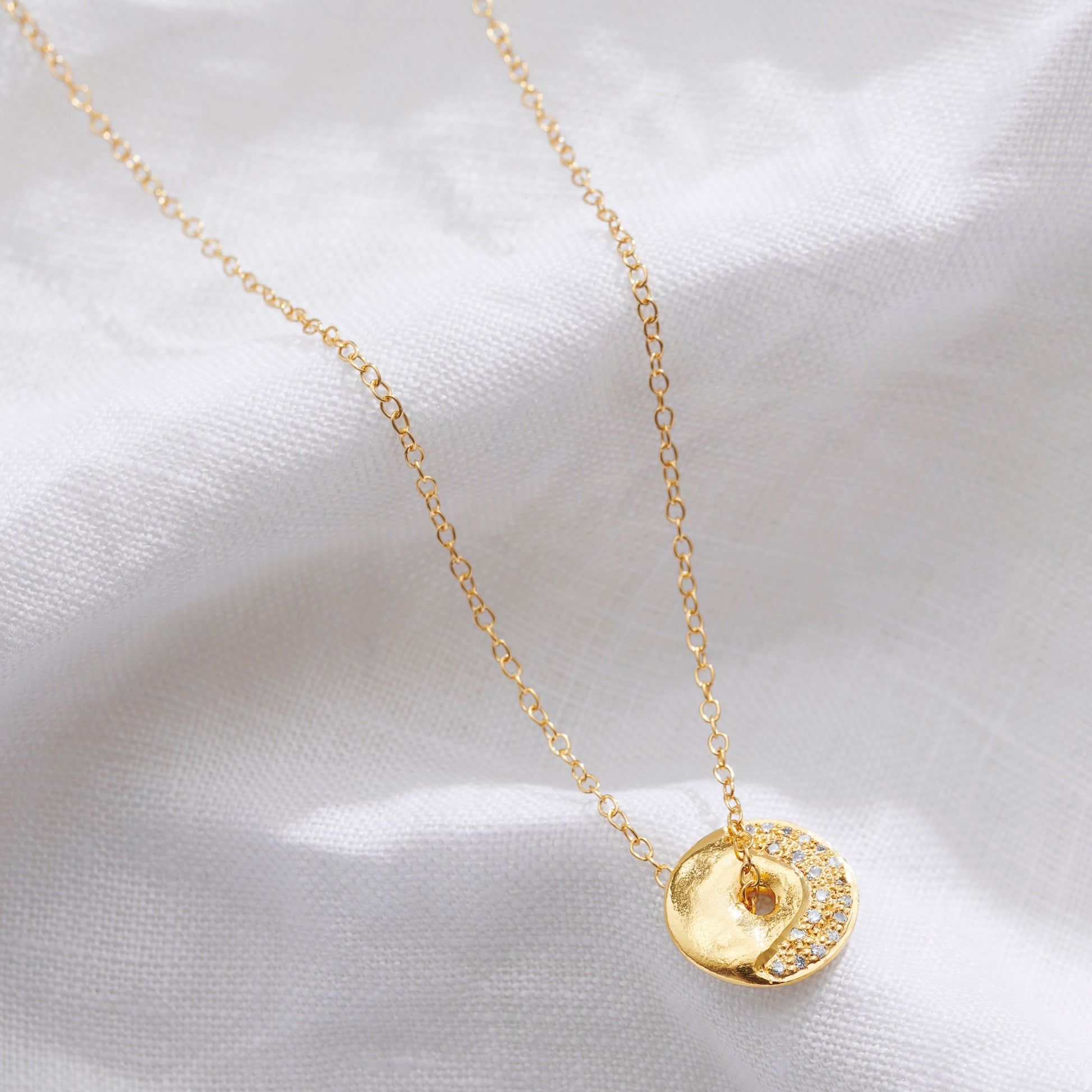 Gold vermeil waxing crescent moon phase necklace with textured disc pendant and small diamonds set in a crescent moon design by Claudette Worters.