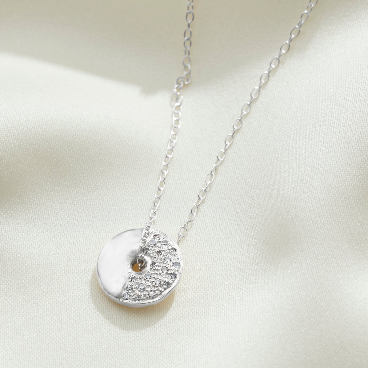 Silver moon phase necklace set with real diamonds to depict the First Quarter moon phase by Claudette Worters