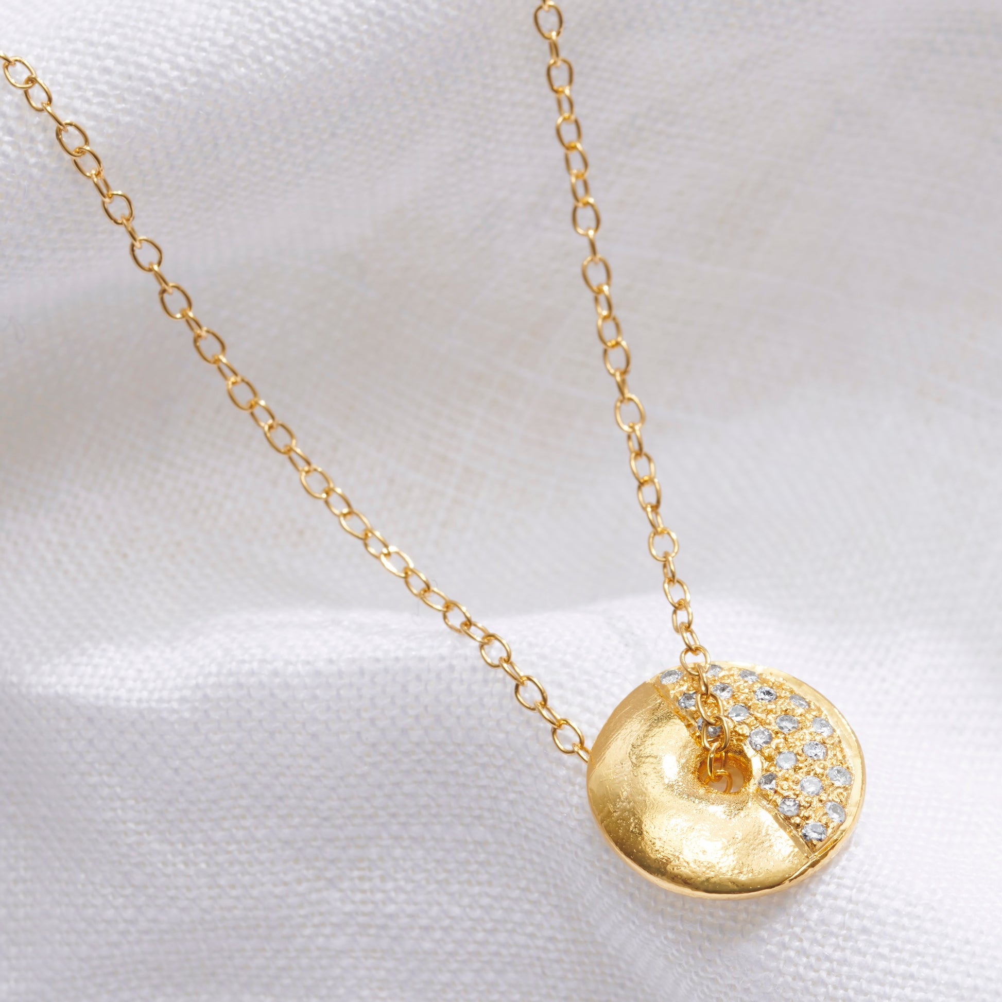 Claudette Worters gold vermeil First Quarter moon phase pendant. Small spinning gold disc pendant with textured lunar surface, tiny natural diamonds showing the first quarter phase of the moon, on a fine chain.