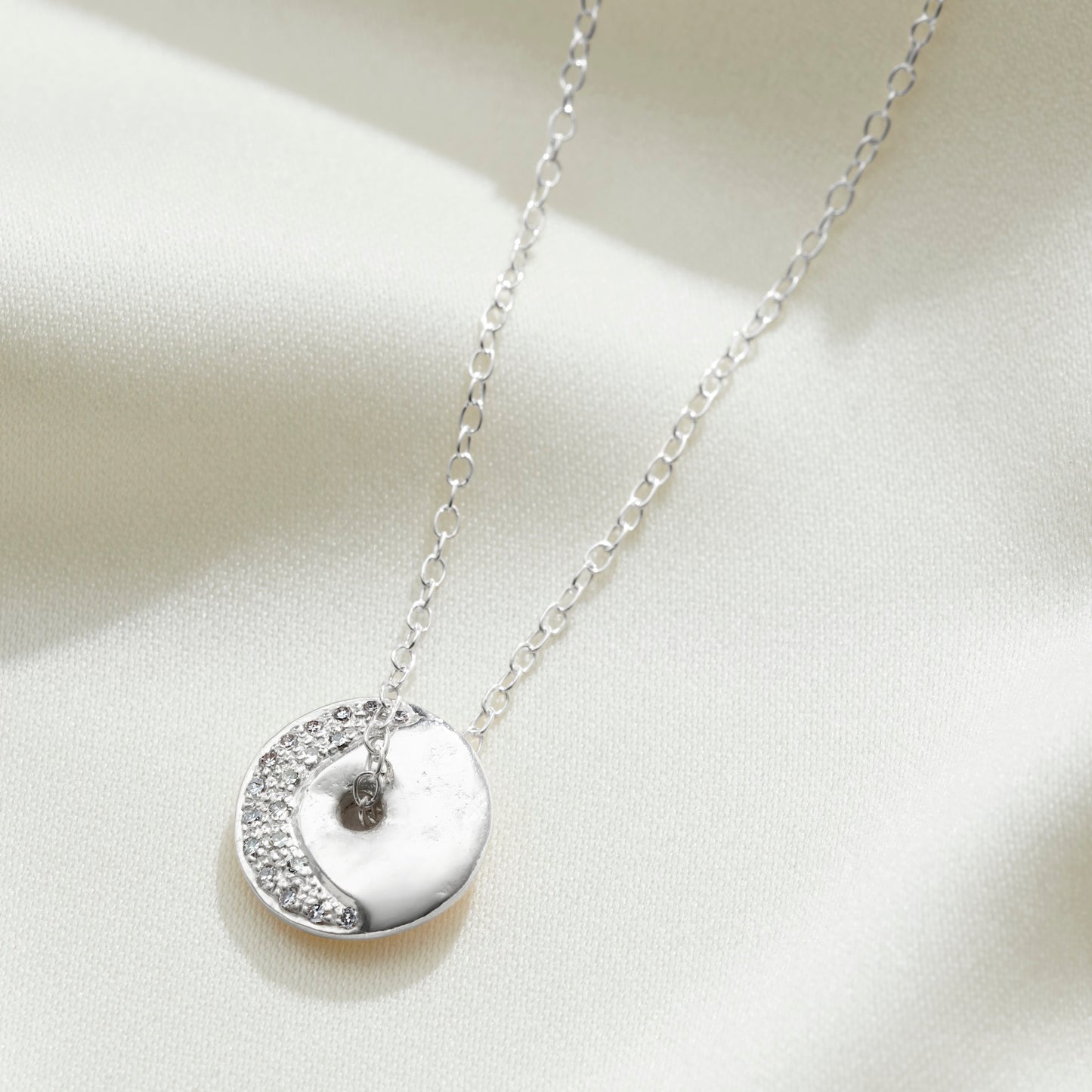 Waning crescent moon phase pendant in sterling silver set with white diamonds on a delicate silver trace chain by Claudette Worters