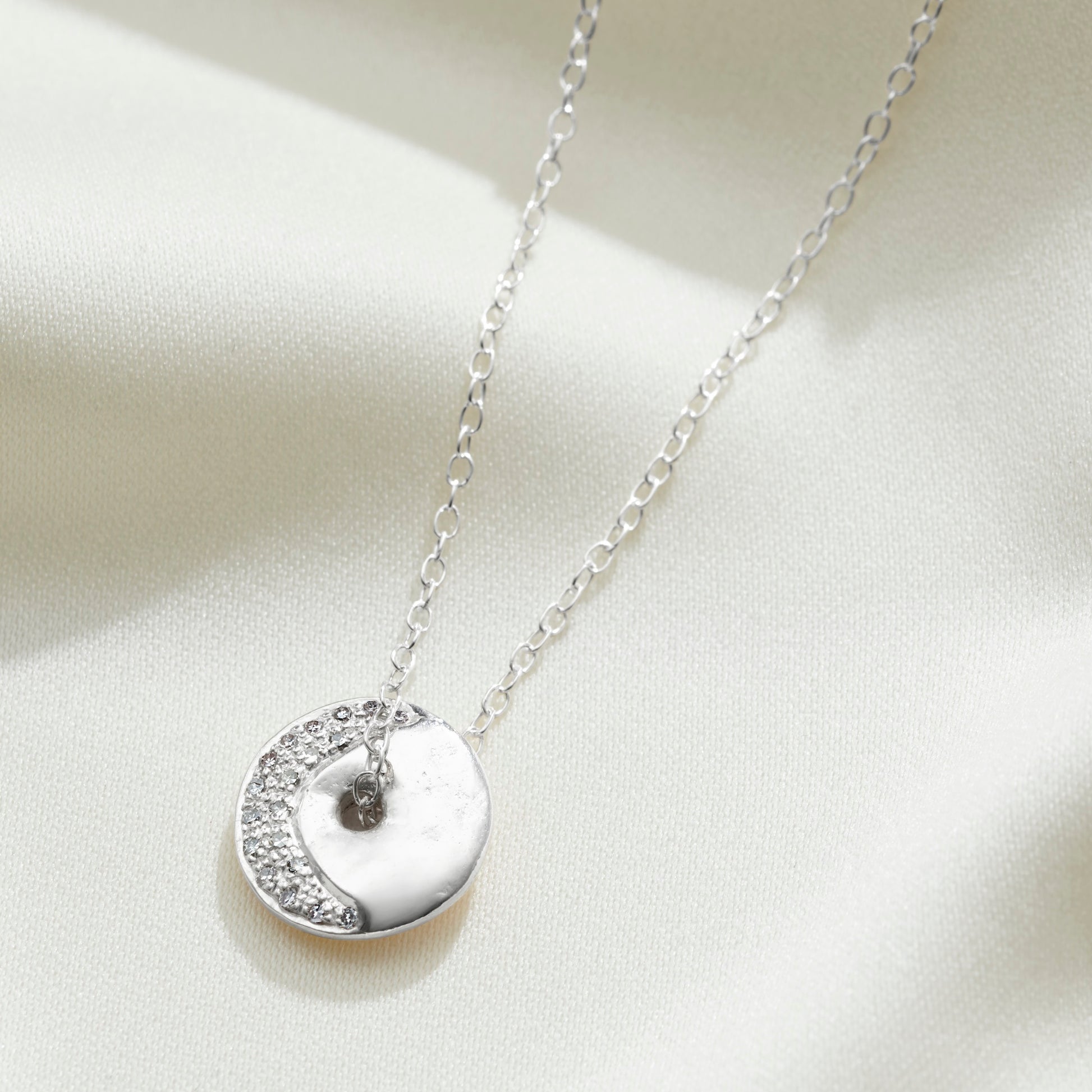 Waning crescent moon phase pendant in sterling silver set with white diamonds on a delicate silver trace chain by Claudette Worters