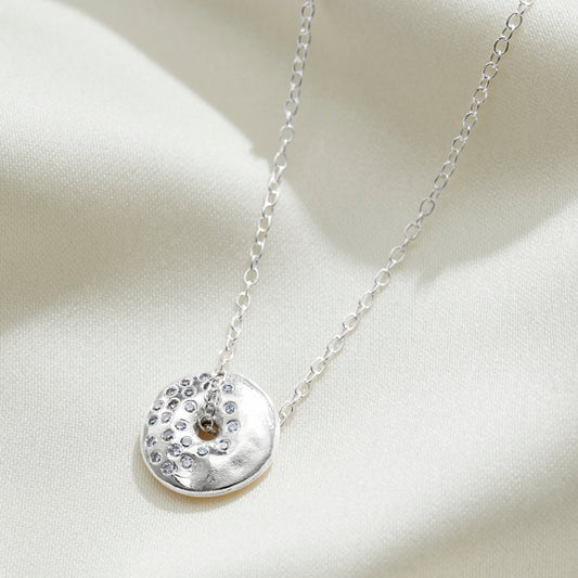 Sterling silver spinning disc shaped pendant necklace depicting the waning moon phase in real diamonds on a fine trace chain by Claudette Worters